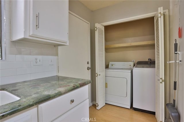 laundry area with separate washer and dryer and light hardwood / wood-style flooring