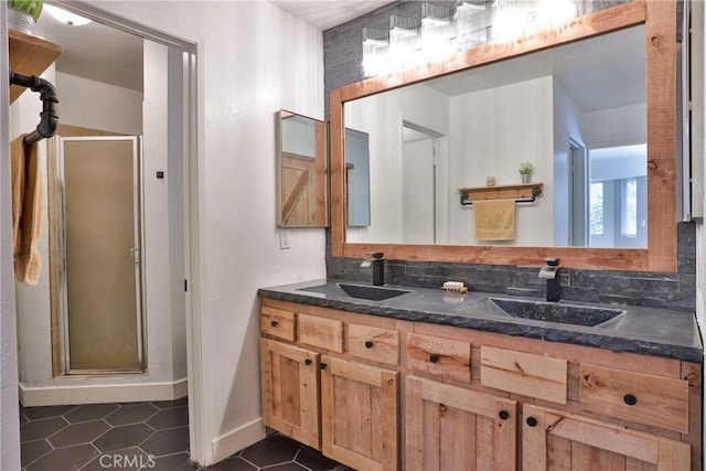 bathroom featuring tile patterned floors, vanity, a shower with shower door, and tasteful backsplash