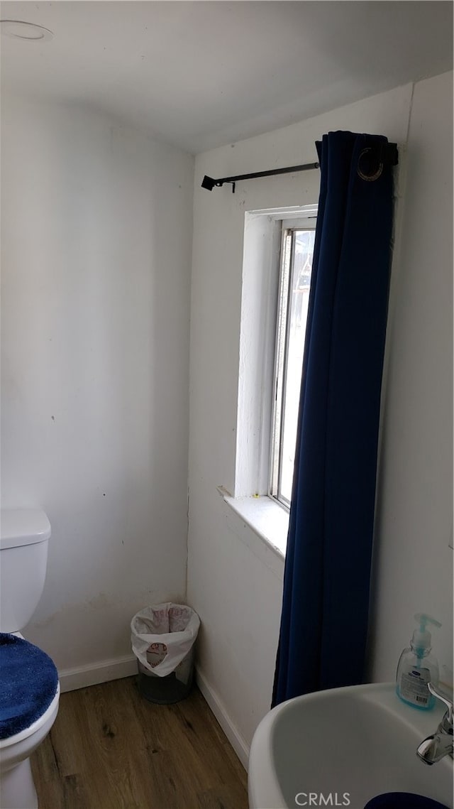 bathroom with toilet, hardwood / wood-style floors, and sink