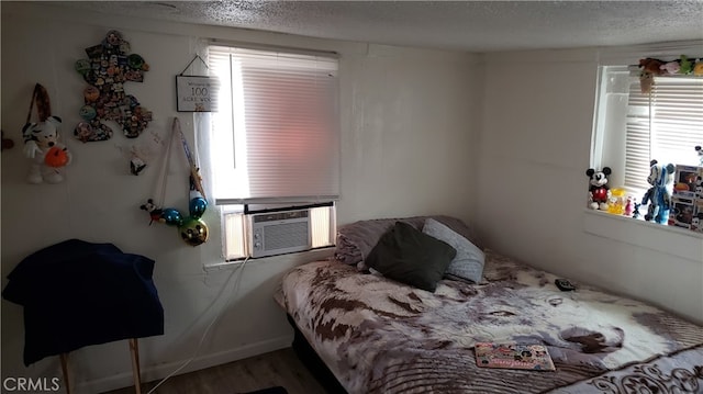 bedroom with a textured ceiling, cooling unit, and multiple windows