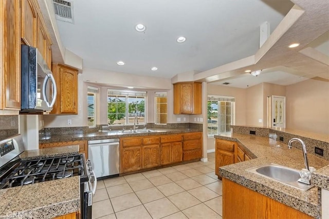 kitchen featuring sink, kitchen peninsula, light tile patterned floors, and stainless steel appliances