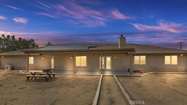 back house at dusk featuring a patio area