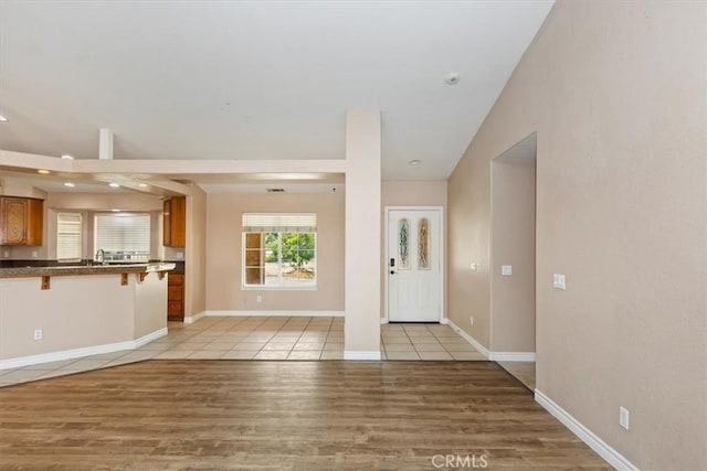 entrance foyer with sink, vaulted ceiling, and light wood-type flooring