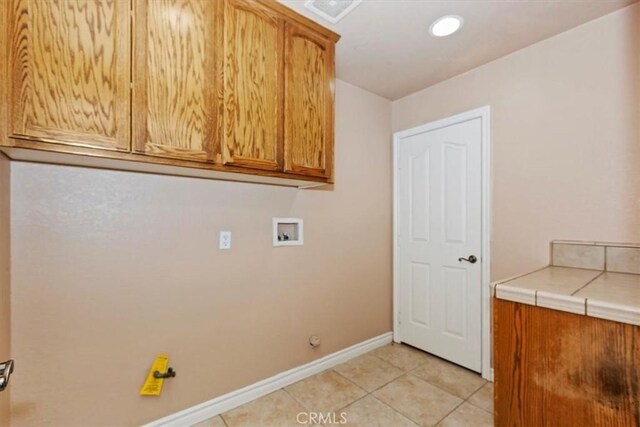 laundry area featuring washer hookup, cabinets, and light tile patterned flooring