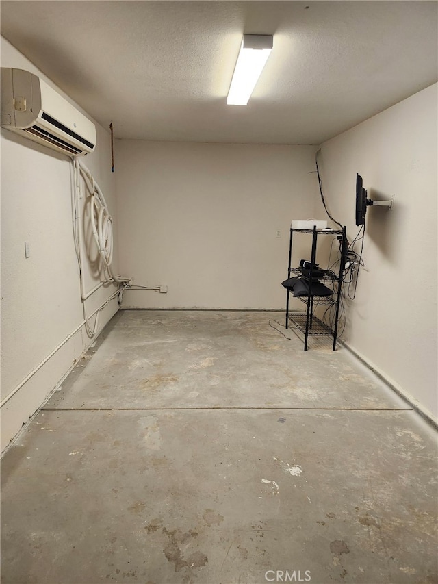 basement with a wall mounted air conditioner and a textured ceiling