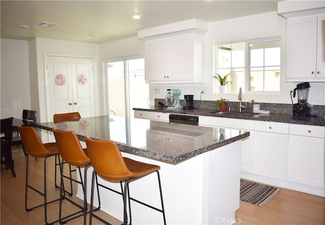 kitchen with a center island, light wood-type flooring, sink, and white cabinetry