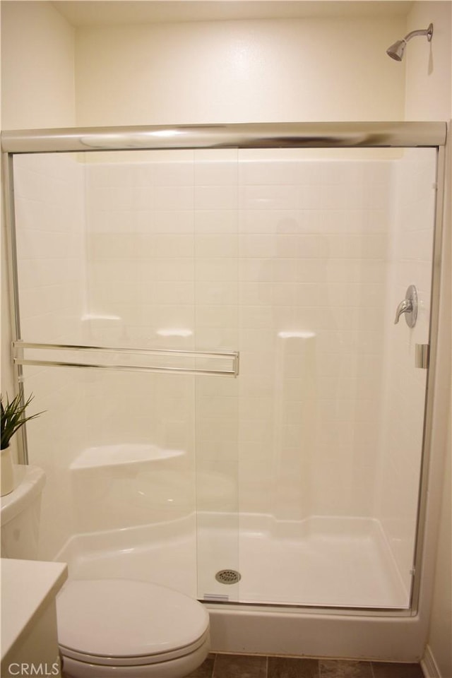 bathroom featuring tile patterned flooring, vanity, toilet, and walk in shower