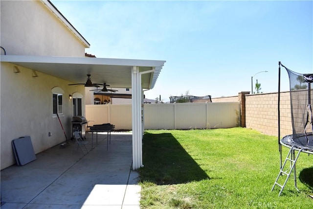 view of yard featuring ceiling fan, a trampoline, and a patio