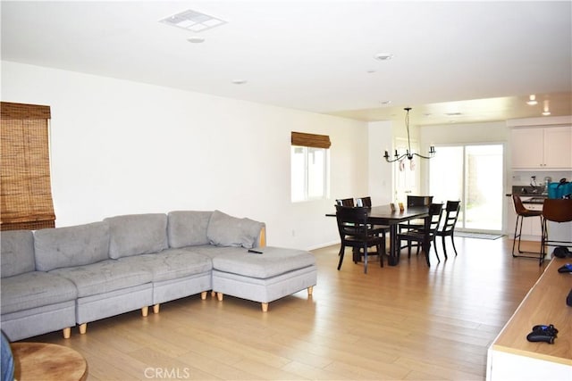 living room with an inviting chandelier and light hardwood / wood-style flooring