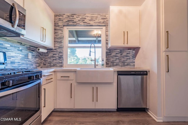 kitchen featuring stainless steel appliances, decorative backsplash, dark wood-type flooring, white cabinets, and sink