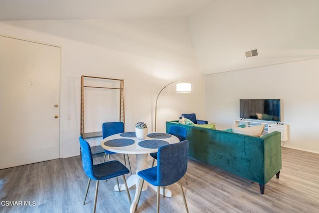 dining space with high vaulted ceiling and wood-type flooring