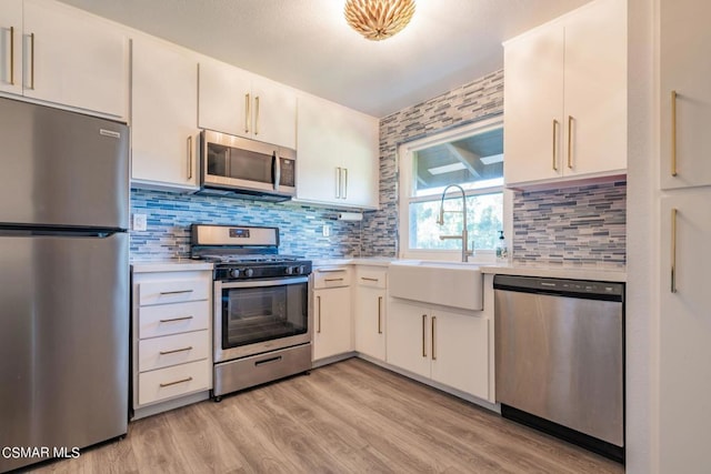 kitchen with stainless steel appliances, decorative backsplash, white cabinets, and sink