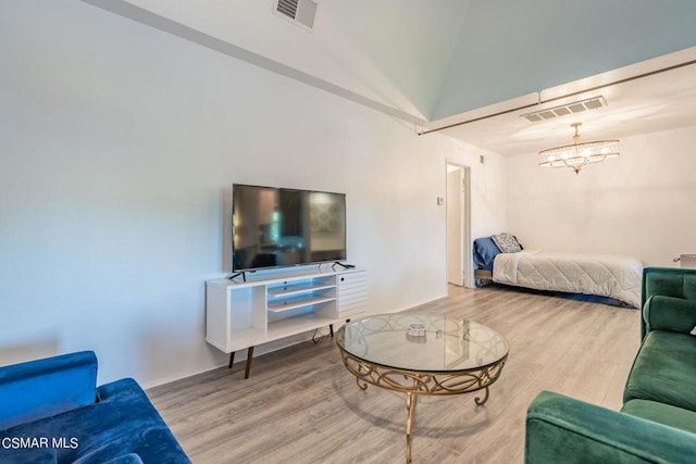 living room with high vaulted ceiling, wood-type flooring, and an inviting chandelier