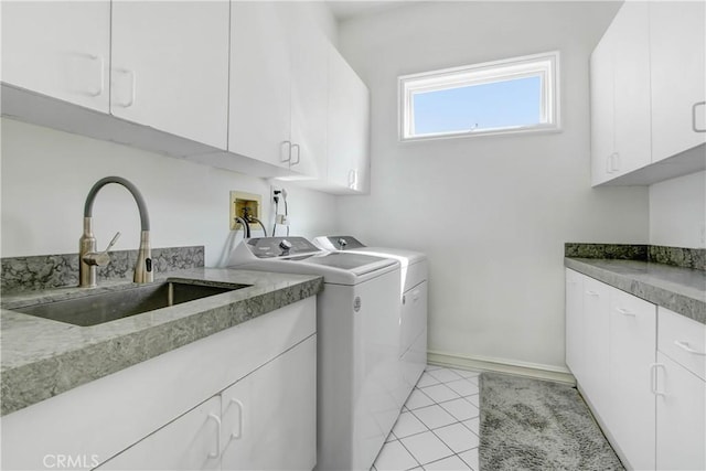 clothes washing area featuring cabinets, light tile patterned floors, washing machine and dryer, and sink