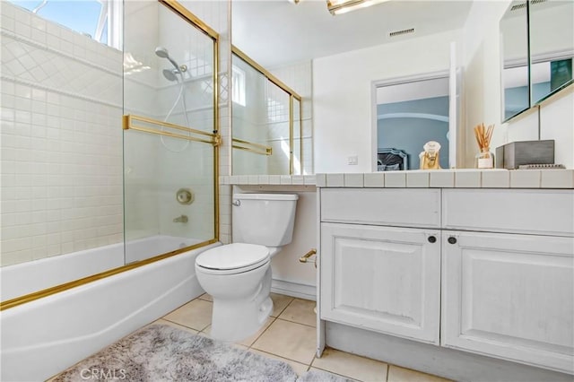 full bathroom with tile patterned flooring, vanity, toilet, and bath / shower combo with glass door