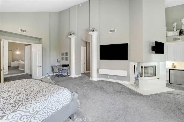 bedroom with carpet, ensuite bathroom, ornate columns, high vaulted ceiling, and stainless steel refrigerator