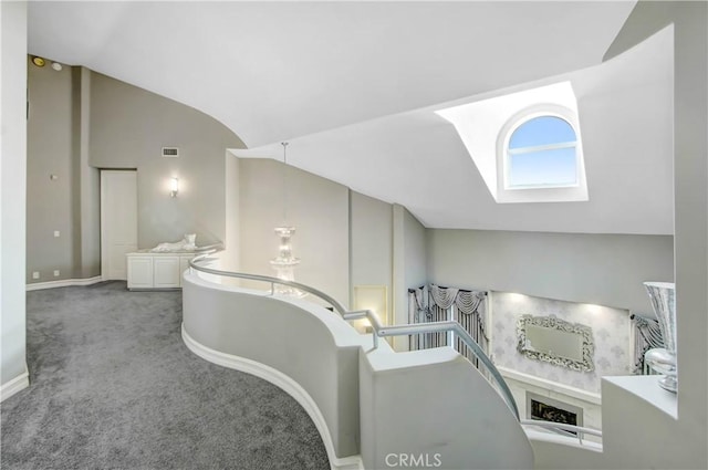 corridor featuring vaulted ceiling with skylight and carpet floors