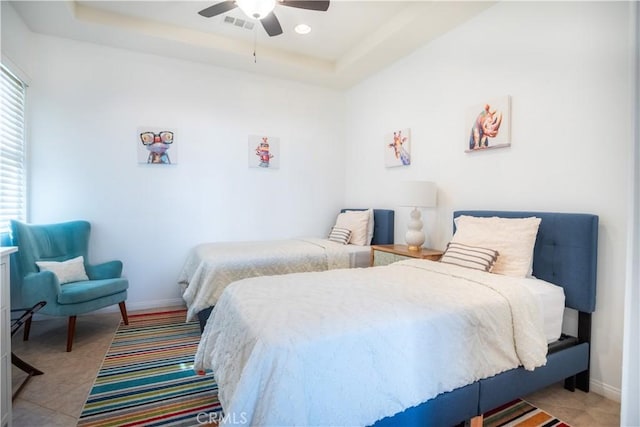 tiled bedroom with a raised ceiling and ceiling fan