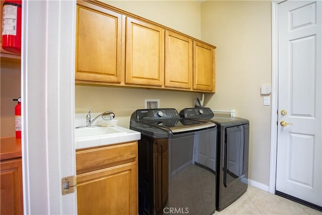 washroom with cabinets, light tile patterned floors, sink, and washing machine and dryer