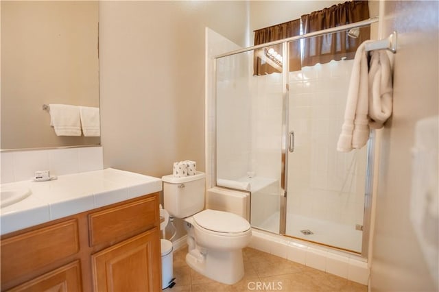 bathroom featuring tile patterned flooring, vanity, a shower with door, and toilet