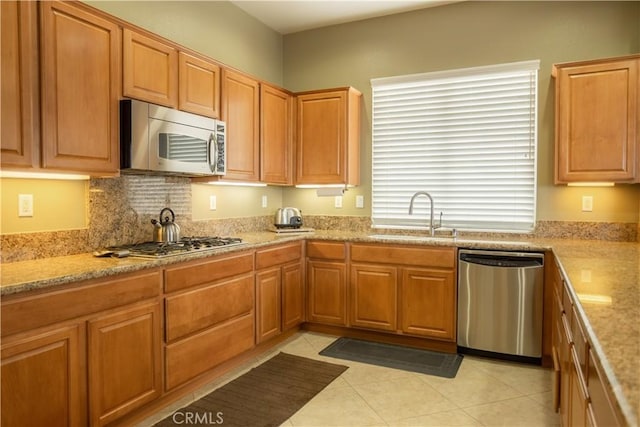 kitchen featuring light tile patterned flooring, sink, light stone countertops, and stainless steel appliances