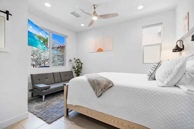 bedroom featuring ceiling fan, a barn door, and light tile patterned floors