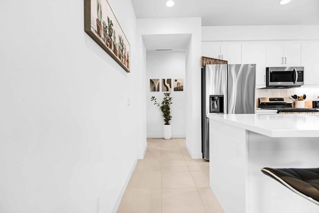 kitchen with backsplash, white cabinetry, light tile patterned floors, and stainless steel appliances