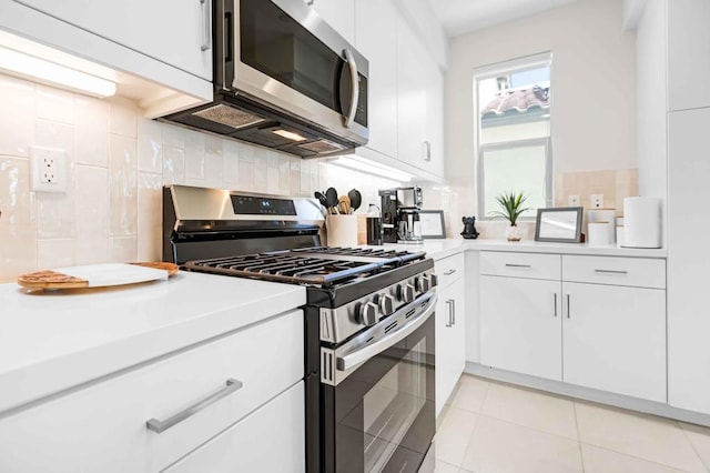 kitchen featuring light tile patterned floors, appliances with stainless steel finishes, decorative backsplash, and white cabinets