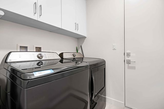 clothes washing area with washer and dryer and cabinets