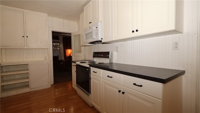 kitchen featuring wood walls, dark wood-type flooring, white appliances, and white cabinetry