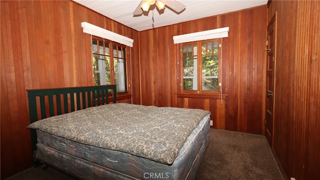 carpeted bedroom with wood walls and ceiling fan