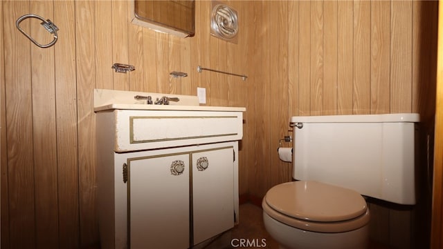 bathroom with vanity, wooden walls, and toilet