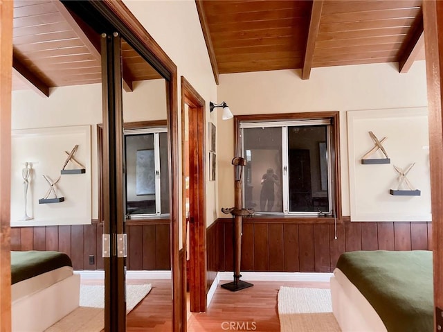 interior space with wood ceiling, vaulted ceiling with beams, light wood-type flooring, and wooden walls