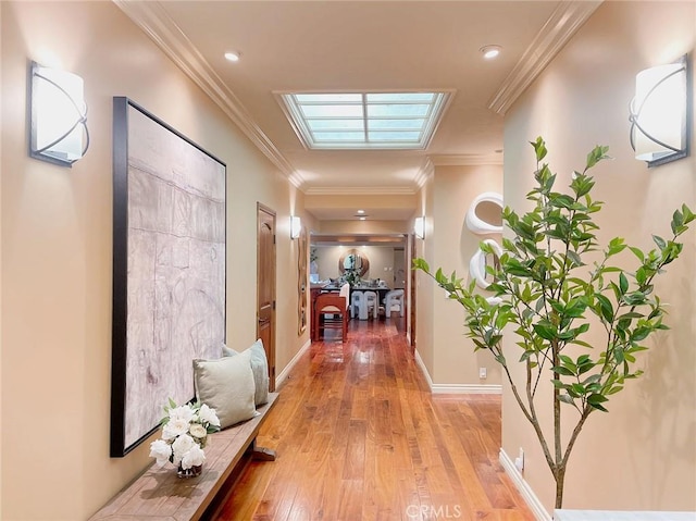 hall with light hardwood / wood-style floors, ornamental molding, and a skylight