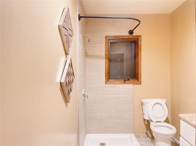 bathroom featuring vanity, toilet, and a tile shower