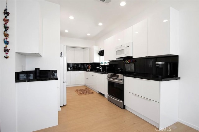 kitchen with white cabinets, backsplash, and light hardwood / wood-style flooring