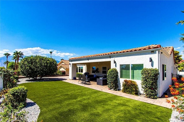 back of house with a patio, outdoor lounge area, and a lawn