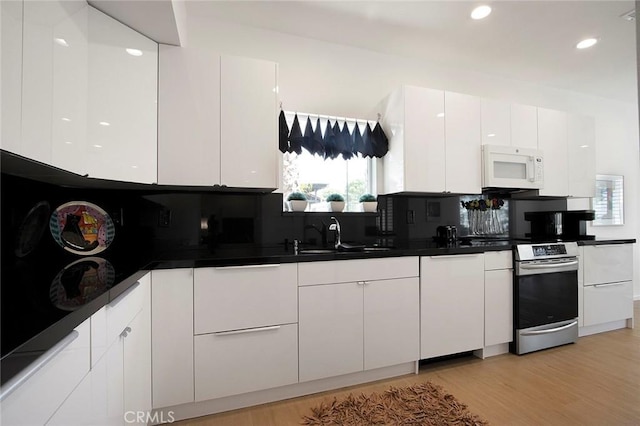 kitchen featuring sink, white cabinetry, light wood-type flooring, stainless steel electric stove, and decorative backsplash