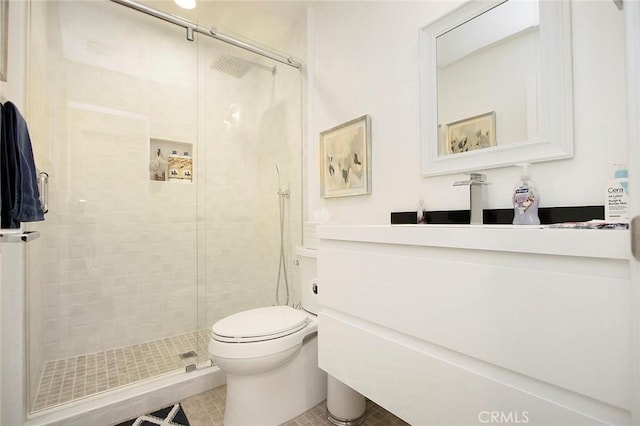 bathroom featuring tile patterned floors, vanity, toilet, and a shower with shower door