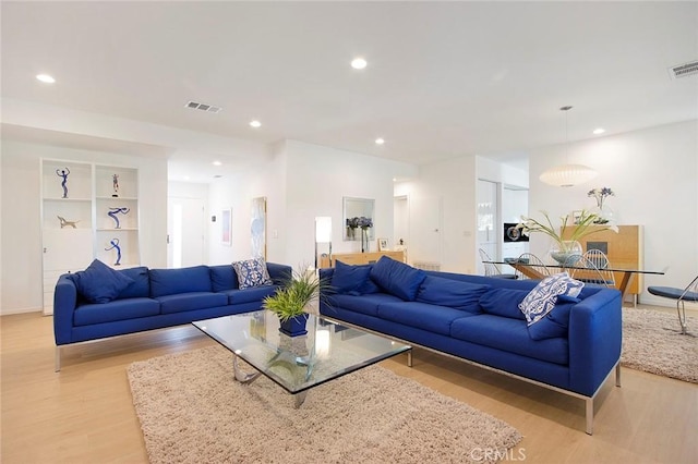 living room featuring built in features and light wood-type flooring