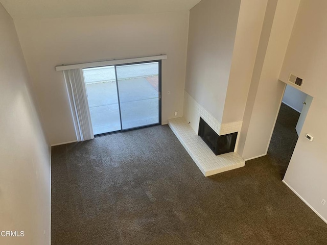 unfurnished living room featuring a brick fireplace and dark colored carpet