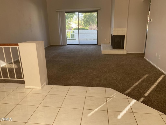 unfurnished living room featuring a tile fireplace and carpet flooring