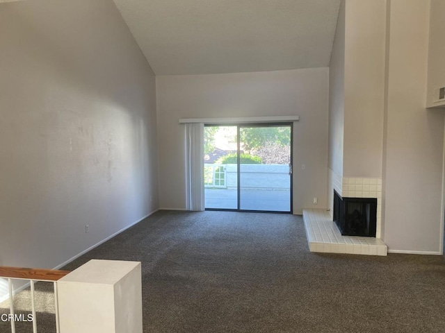 unfurnished living room with high vaulted ceiling, a brick fireplace, and dark colored carpet