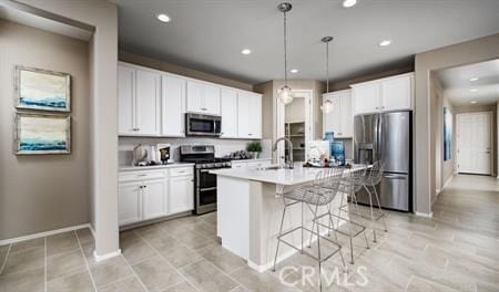 kitchen with an island with sink, white cabinetry, pendant lighting, and stainless steel appliances