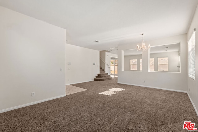 spare room featuring carpet and a notable chandelier