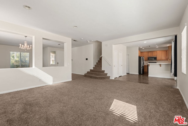 unfurnished living room with dark colored carpet and an inviting chandelier