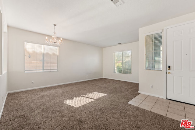 foyer featuring a chandelier and carpet flooring