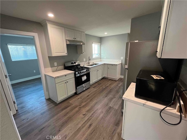 kitchen featuring stainless steel range with gas cooktop, sink, dark wood-type flooring, and white cabinets