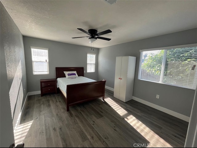 bedroom featuring a textured ceiling, multiple windows, ceiling fan, and dark hardwood / wood-style flooring