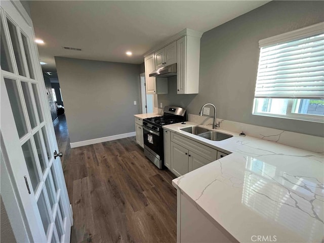 kitchen with white cabinets, sink, stainless steel gas range, dark wood-type flooring, and light stone countertops